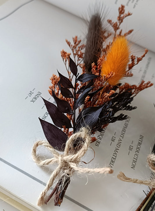 black Dried floral boutonniere tied with twine on an open book
