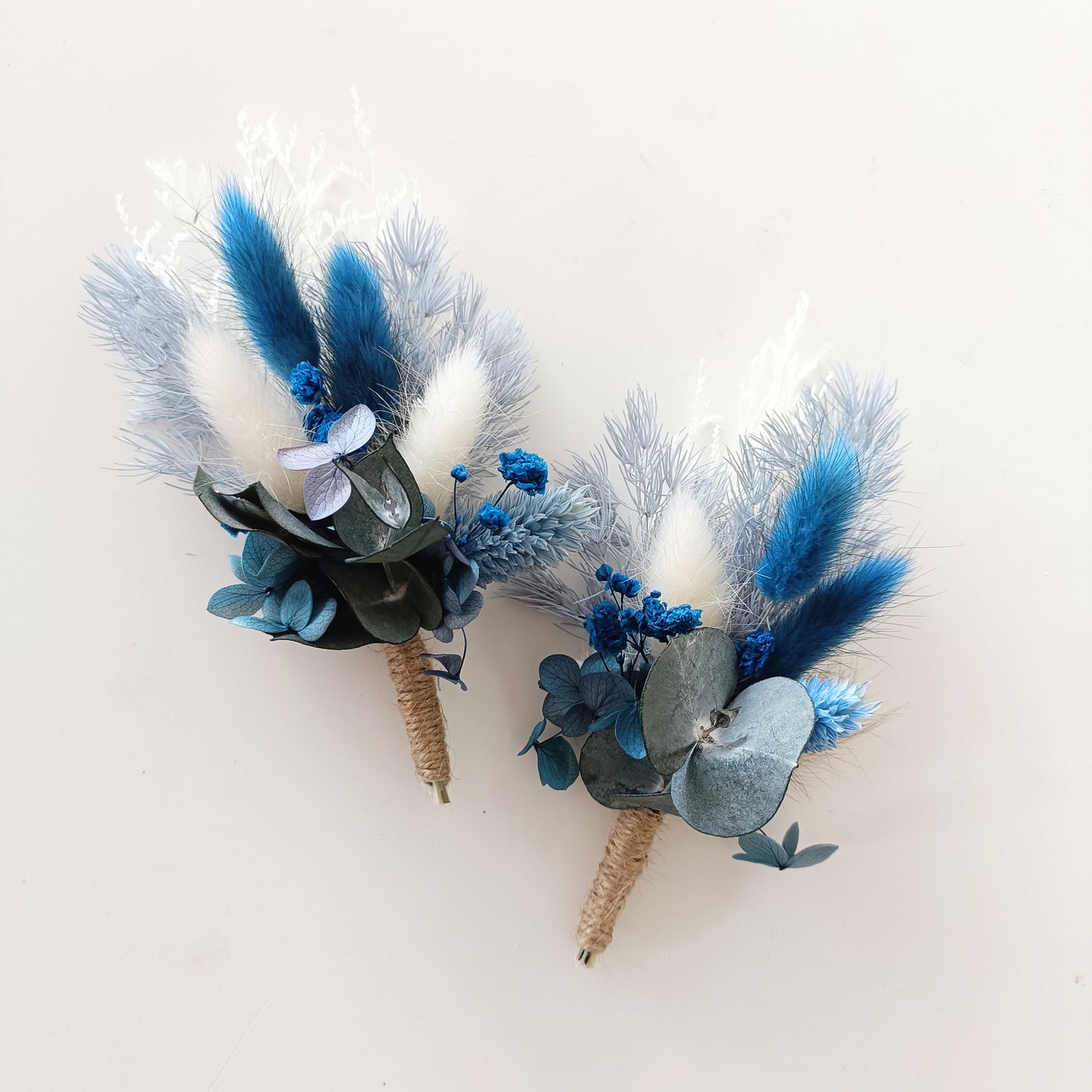 Rustic groom buttonholes in navy and neutral tones with dried florals and natural textures