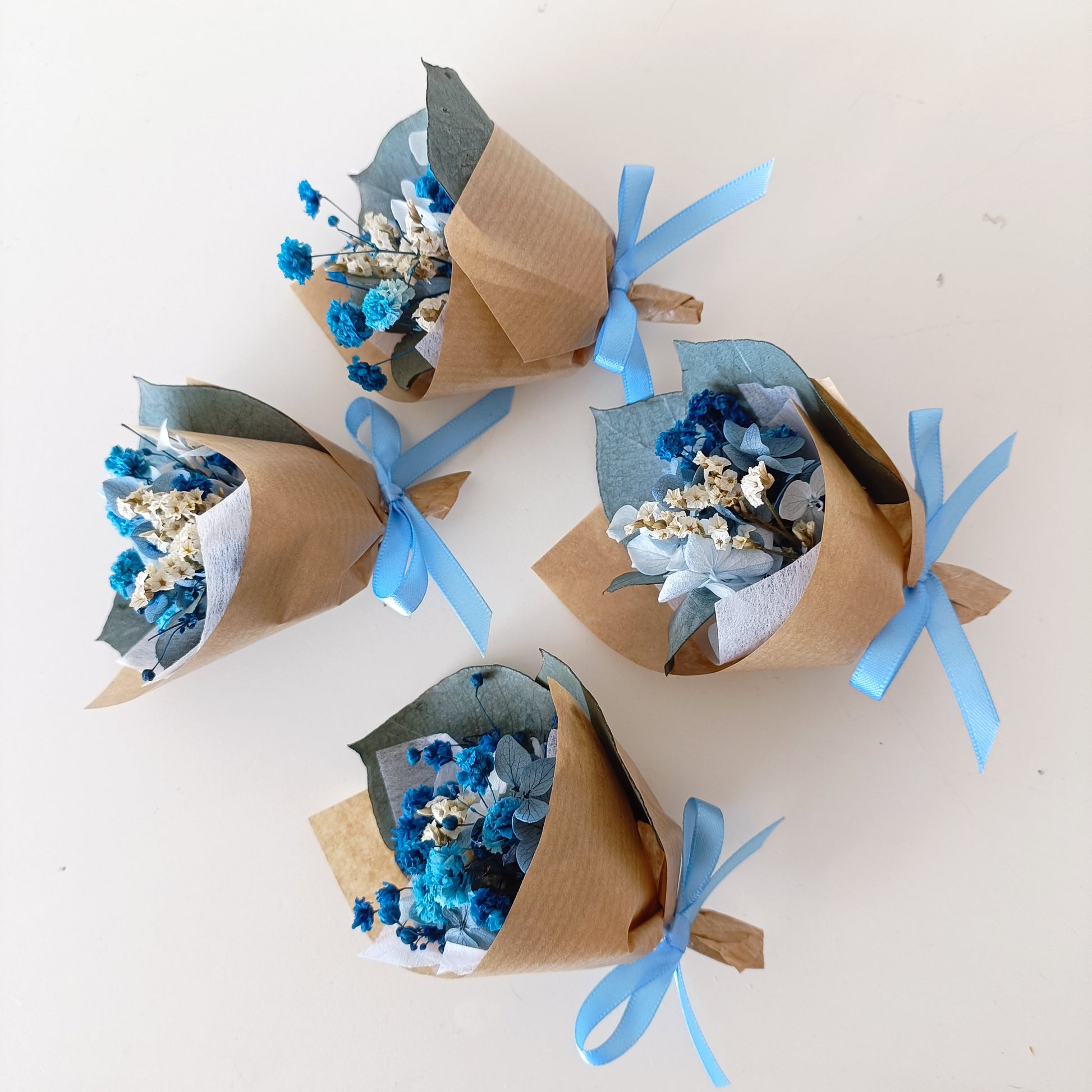 Blue mini dried flower arrangements for wedding favours, baby showers, or thank you gifts. Wrapped in kraft paper and tied with a satin ribbon.