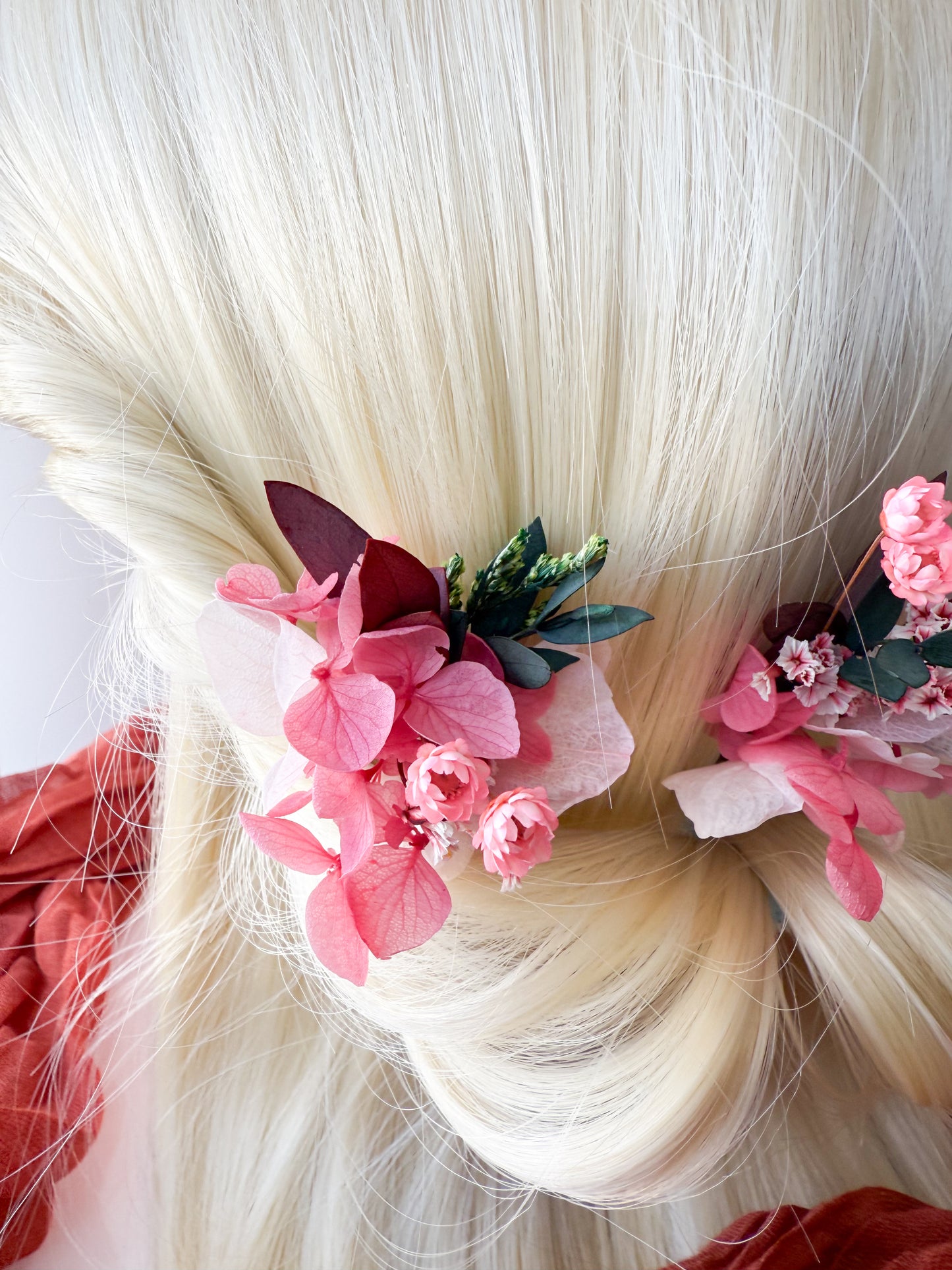 Soft blush wedding flower hair pins styled in a blonde low bun, ideal for garden or boho weddings