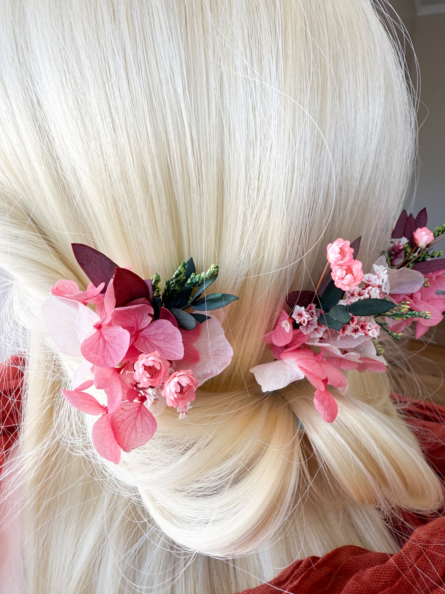 Elegant side profile of a wedding hairstyle with blush-toned flower clips and preserved greenery