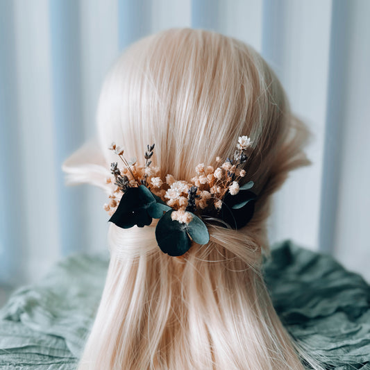 Bridal hair pins with preserved eucalyptus, blush-toned florals, and pearl accents, styled in a soft half-up wedding hairstyle