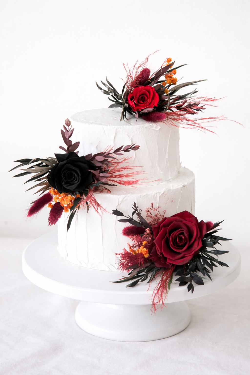 Elegant wedding cake styling with black and burgundy roses with deep red dried florals in a rustic, modern botanical palette.