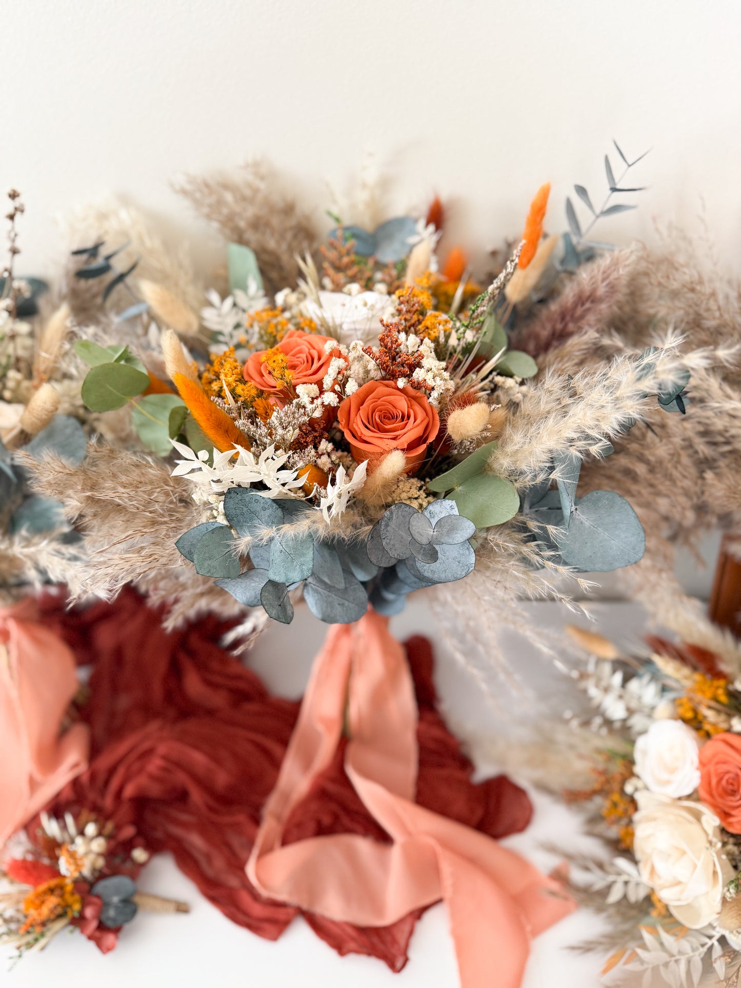 Dried flower bridal bouquet in burnt orange, beige, and dusty blue tones with preserved roses, eucalyptus, and pampas grass — boho rustic Australian wedding bouquet.