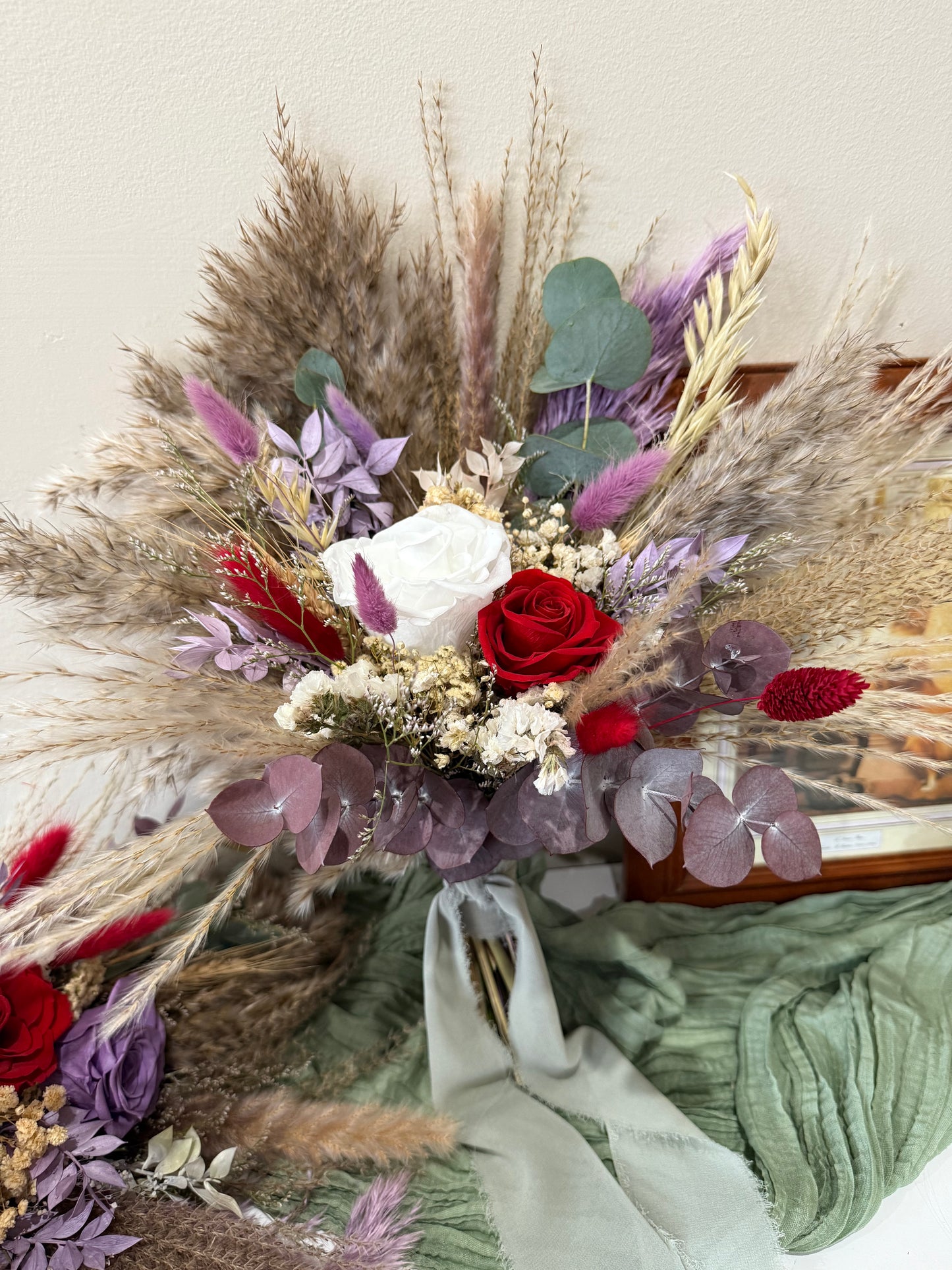 Bouquet of dried flowers and herbs with red and white roses on a neutral background