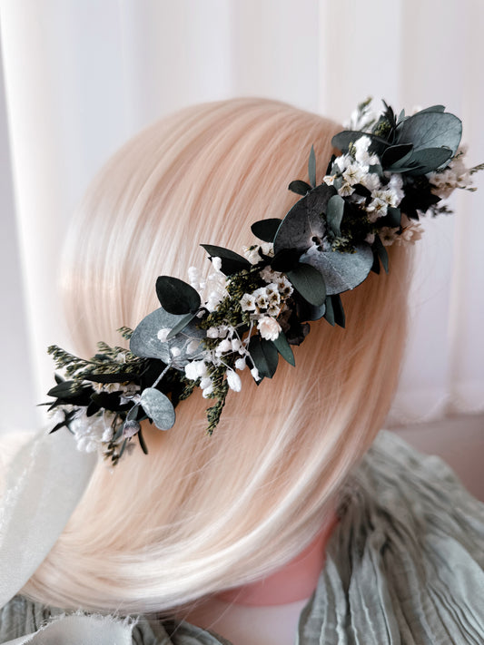 Boho-style dried flower crown with eucalyptus and white blooms on blonde mannequin head, side view.