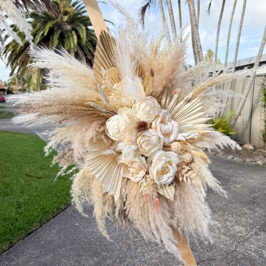 Wedding ceremony backdrop with pampas grass and sola peonies, styled in neutral tones for elegant outdoor celebrations.