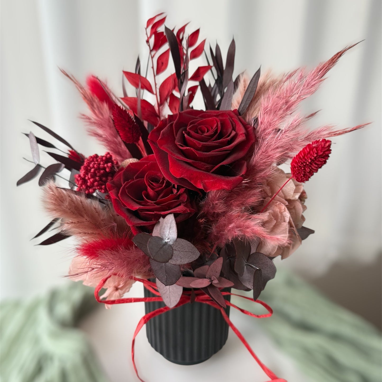 Bouquet of red flowers with pampas grass on a mannequin against a white curtain background