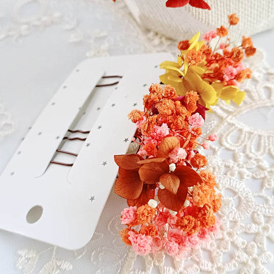 set of two handcrafted hair clips made from preserved colourful flowers. The clips are detailed with delicate pearl clusters and accented with natural textures for a bohemian feel.