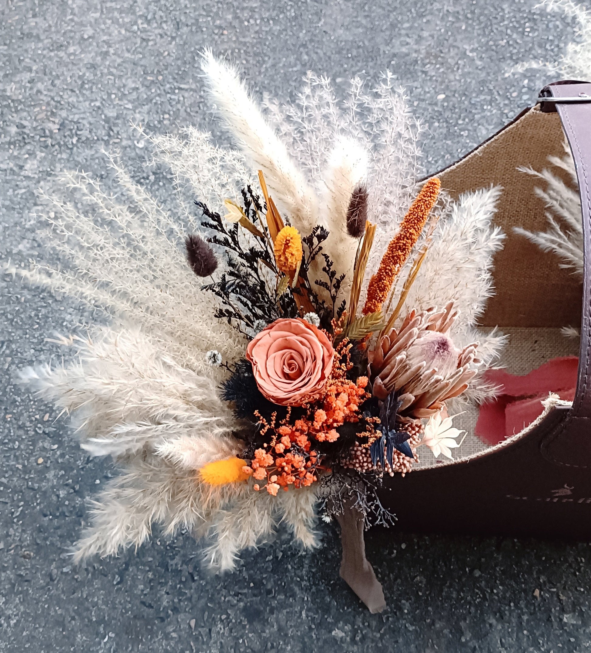 This handcrafted bouquet combines the natural beauty of dried pampas grass with preserved roses and wildflowers, creating a bohemian-inspired arrangement perfect for weddings or home decor. The soft, earthy tones and unique textures make it a stunning centerpiece for any rustic or vintage-themed event