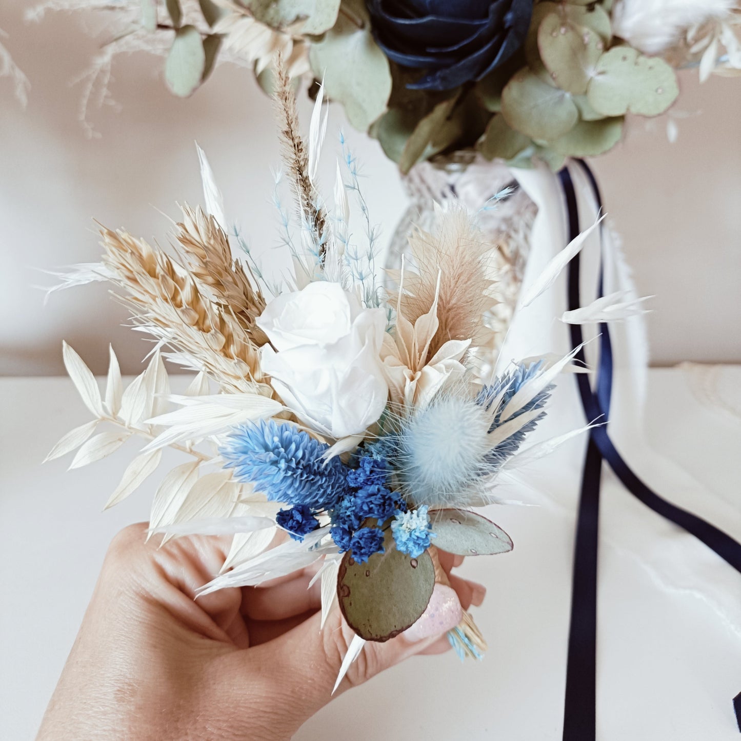 Navy and ivory dried flower boutonniere with sola rose, bunny tail, and preserved foliage – perfect match for groom or groomsmen.