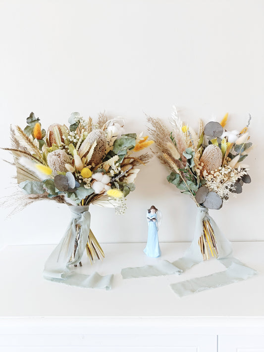 Neutral-toned wedding bouquet featuring dried banksia, yellow billy buttons, eucalyptus, and cotton – hand-tied and wrapped in a soft sage ribbon.