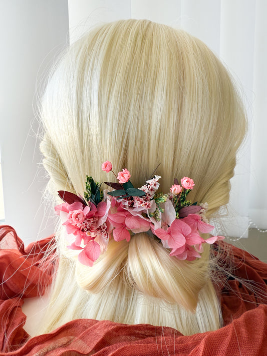 Handmade wedding hair clip set with pink cherry blossoms and preserved greenery in a romantic, soft bridal hairstyle