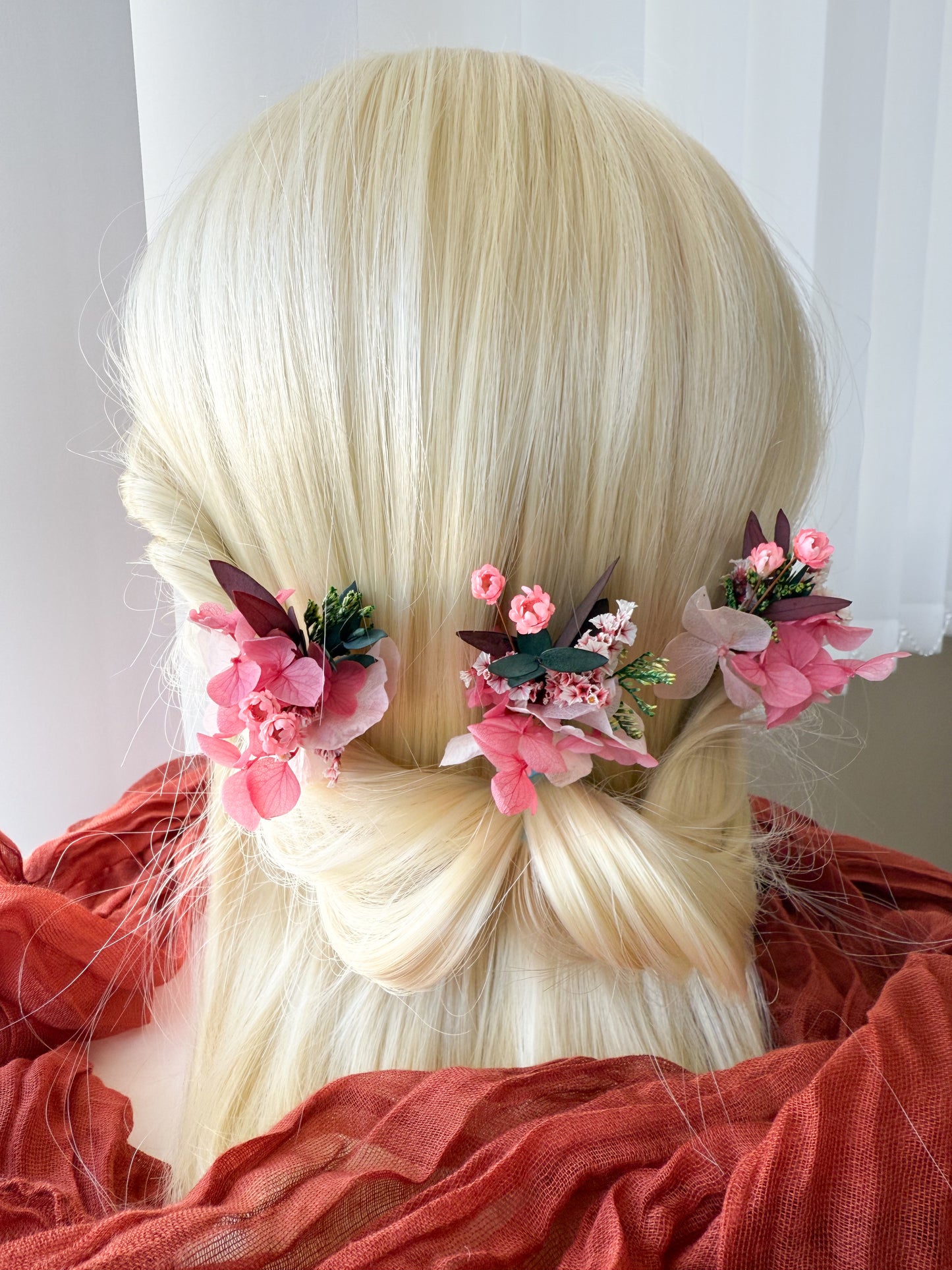 Romantic floral hairpiece set featuring soft pink flowers with greenery, styled in a feminine low bridal bun