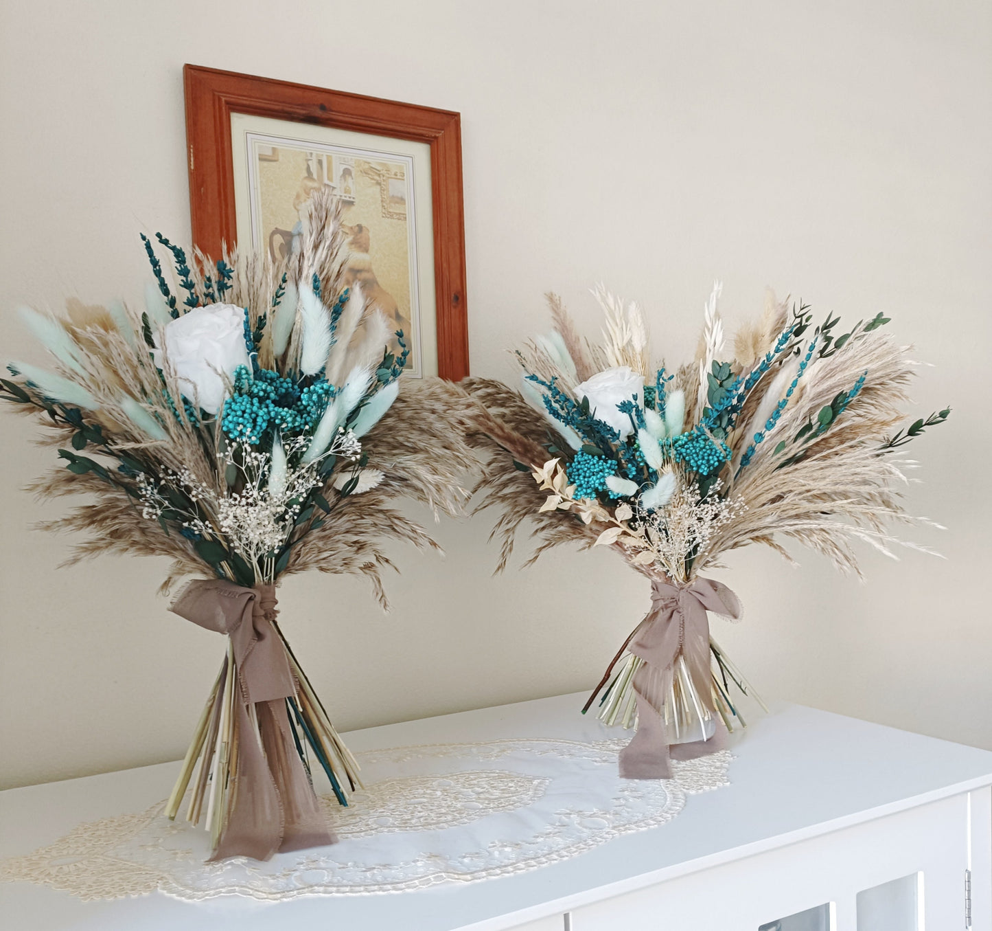 This beautifully crafted wedding bouquet features an elegant mix of blue, white, and natural tones, made from dried flowers and pampas grass. The arrangement exudes a modern rustic charm, with preserved foliage and delicate accents adding a sophisticated touch. Perfect for a contemporary bride, this long-lasting bouquet is ideal for weddings with a natural or bohemian theme. Explore our collection for more unique bridal bouquets and wedding decor inspirations.