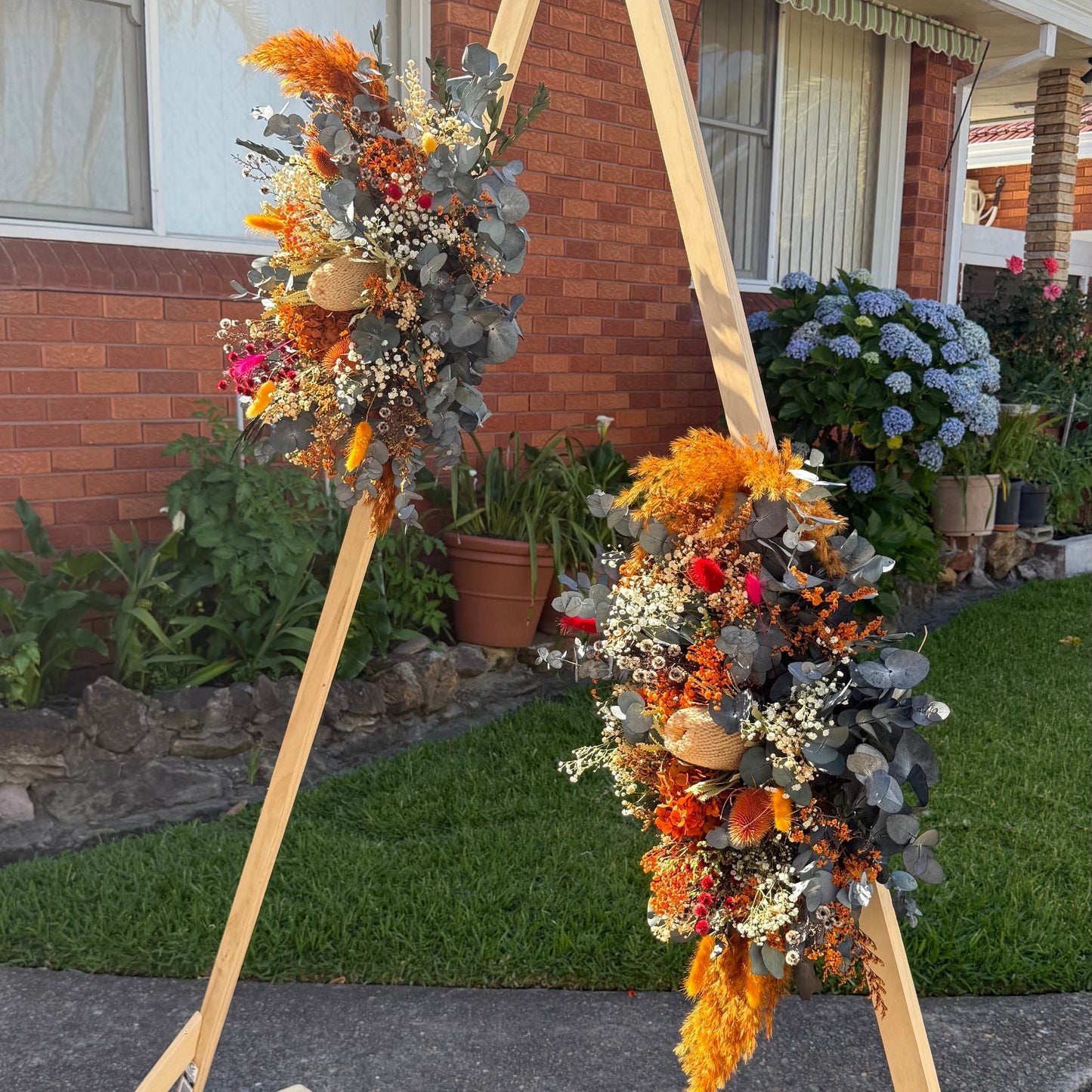 Decorative floral arch with autumn colors in front of a house.