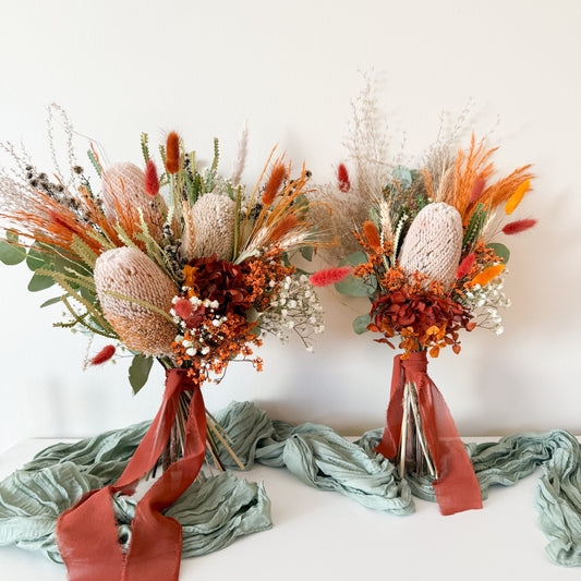 Rustic boho bridal bouquets with dried banksia, hydrangea, and burnt orange flowers tied with rust silk ribbons