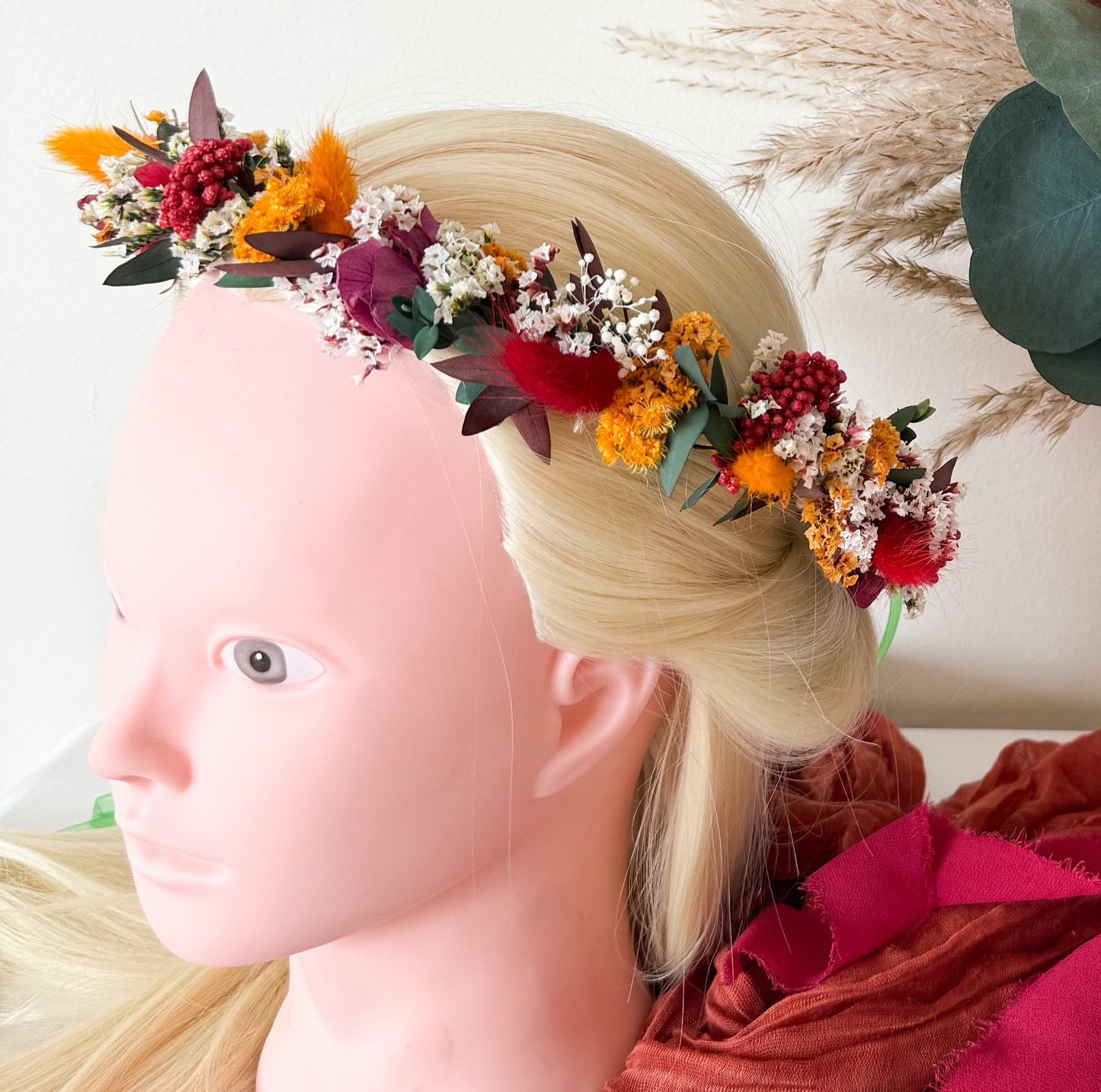 Boho flower crown made of dried flowers in orange, yellow, burgundy, and purple tones, styled on a mannequin head — perfect bridal hair accessory for rustic or autumn weddings.