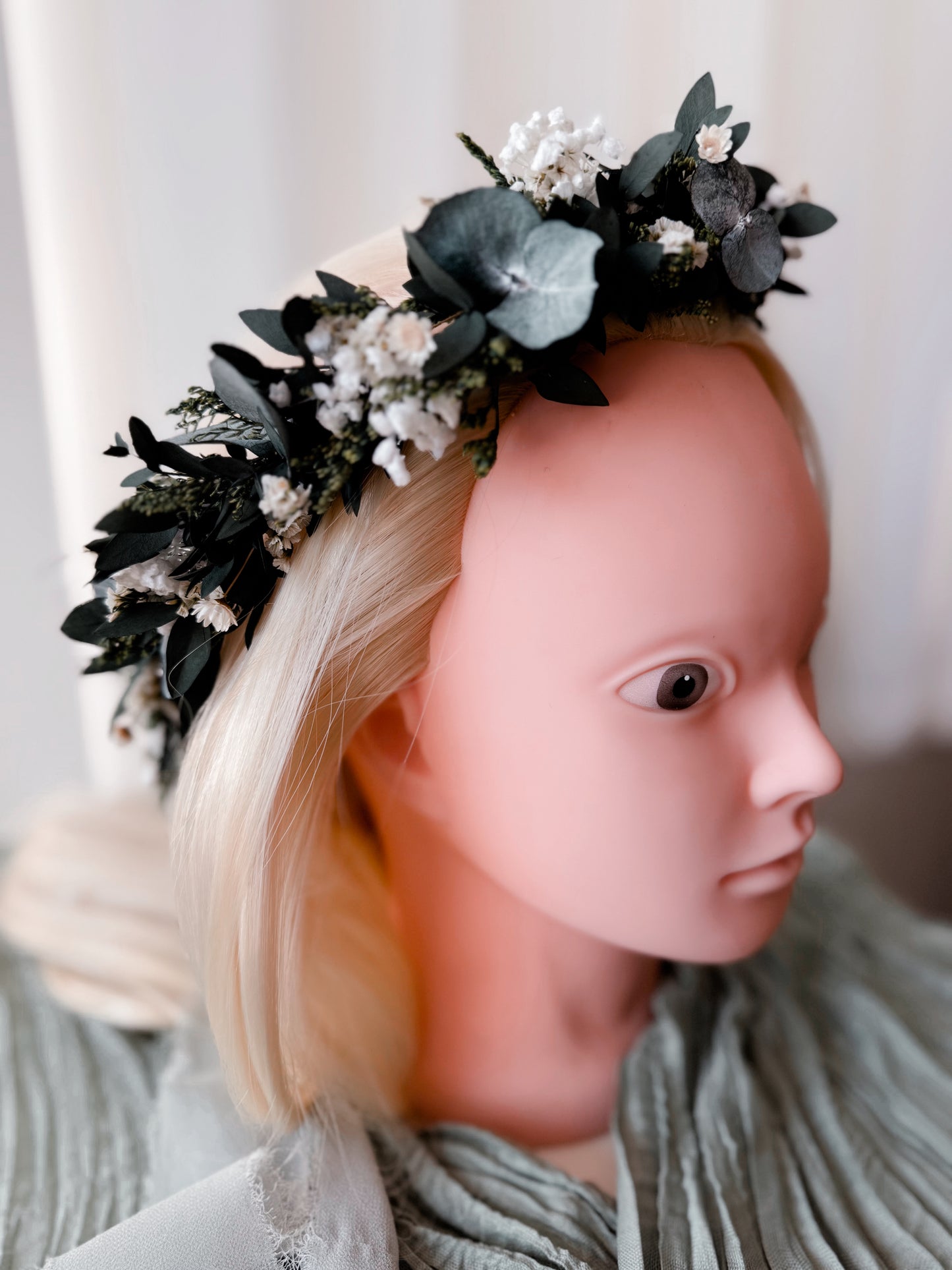 Mannequin head with a floral headband on a neutral background