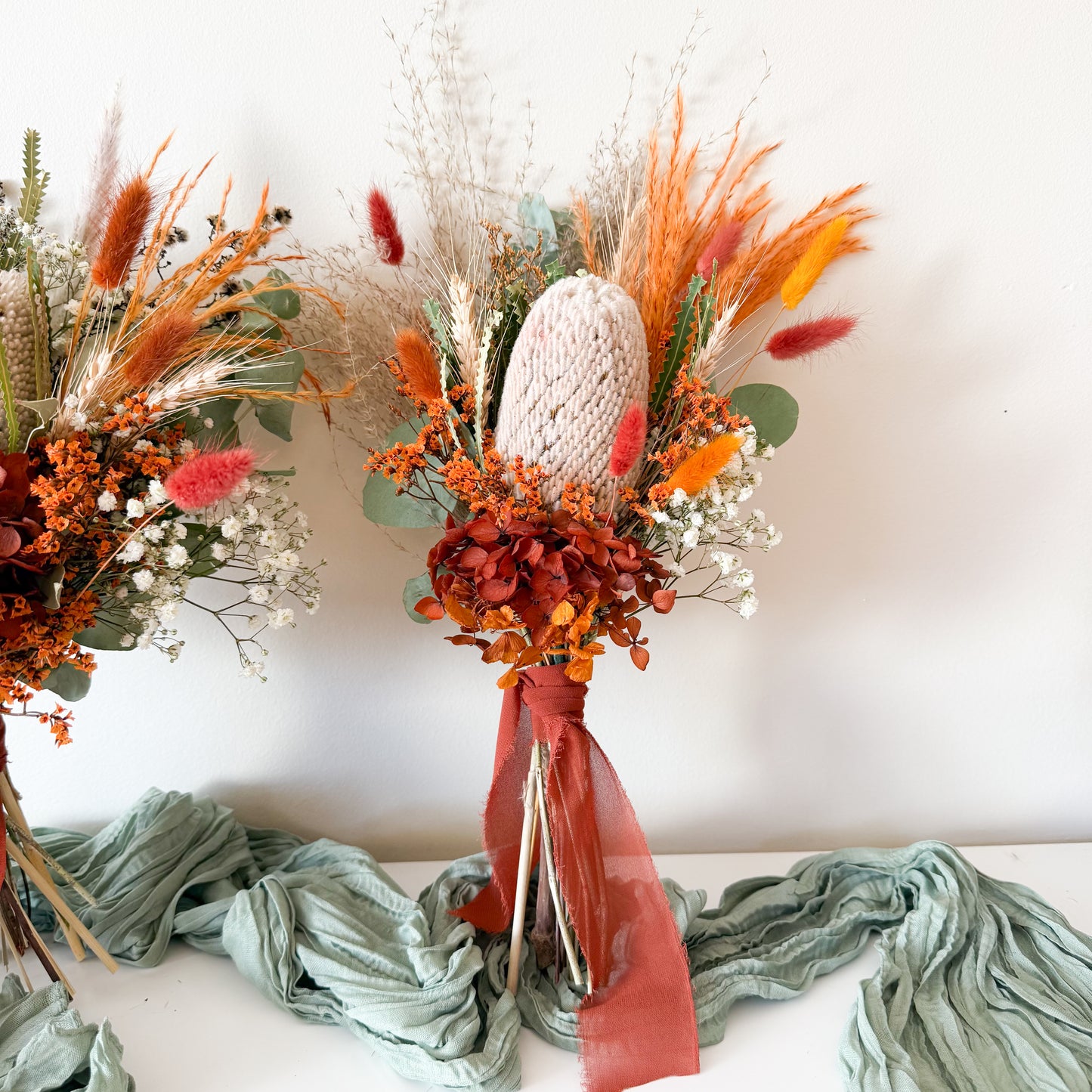 Handcrafted wedding bouquets with preserved banksia, bunny tails, and terracotta accents on white background