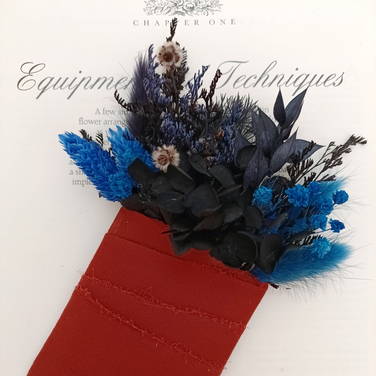 Modern dried flower boutonniere in navy blue and black with preserved hydrangea and terracotta ribbon