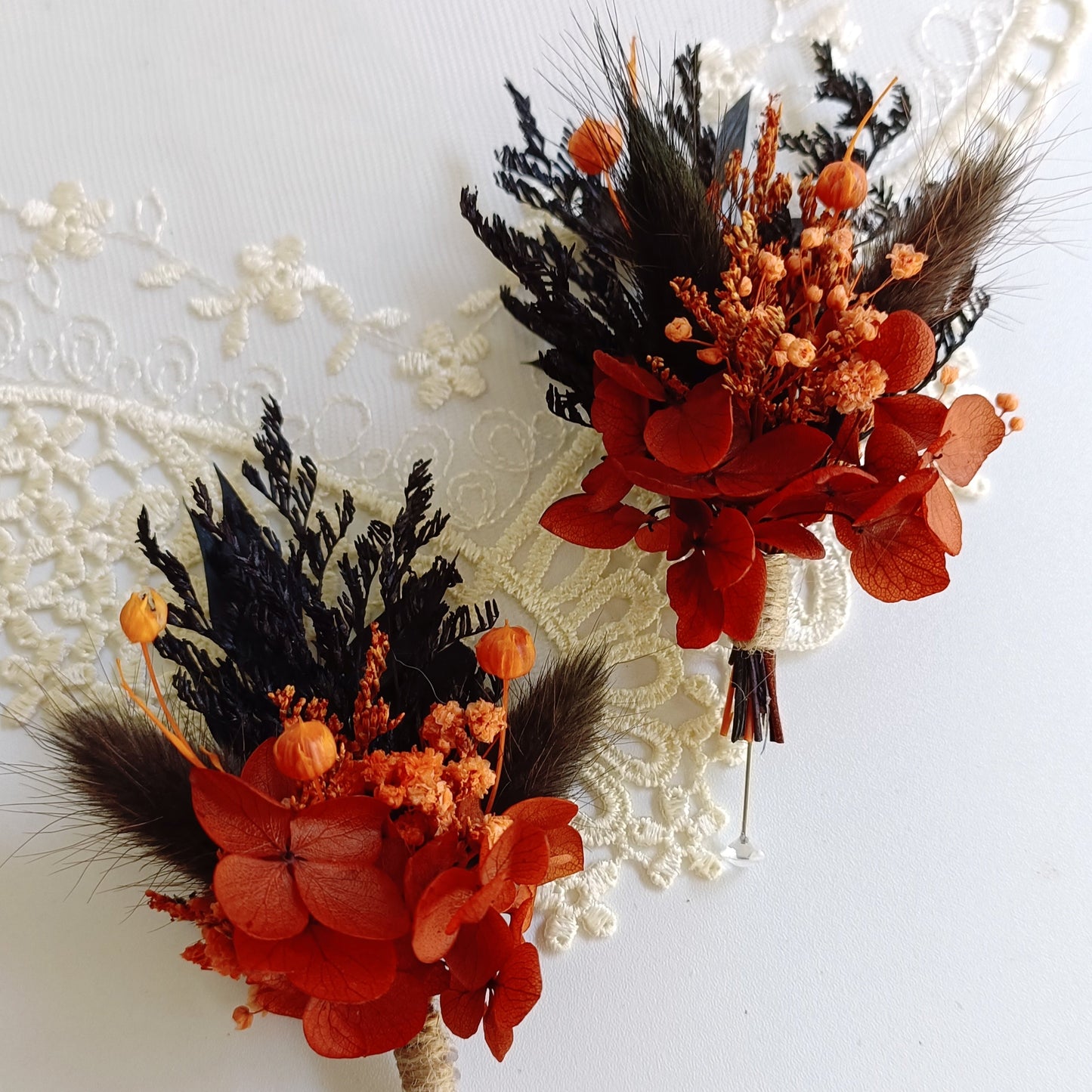 Rustic dried wedding buttonhole with orange hydrangea, navy foliage, and natural seed pods