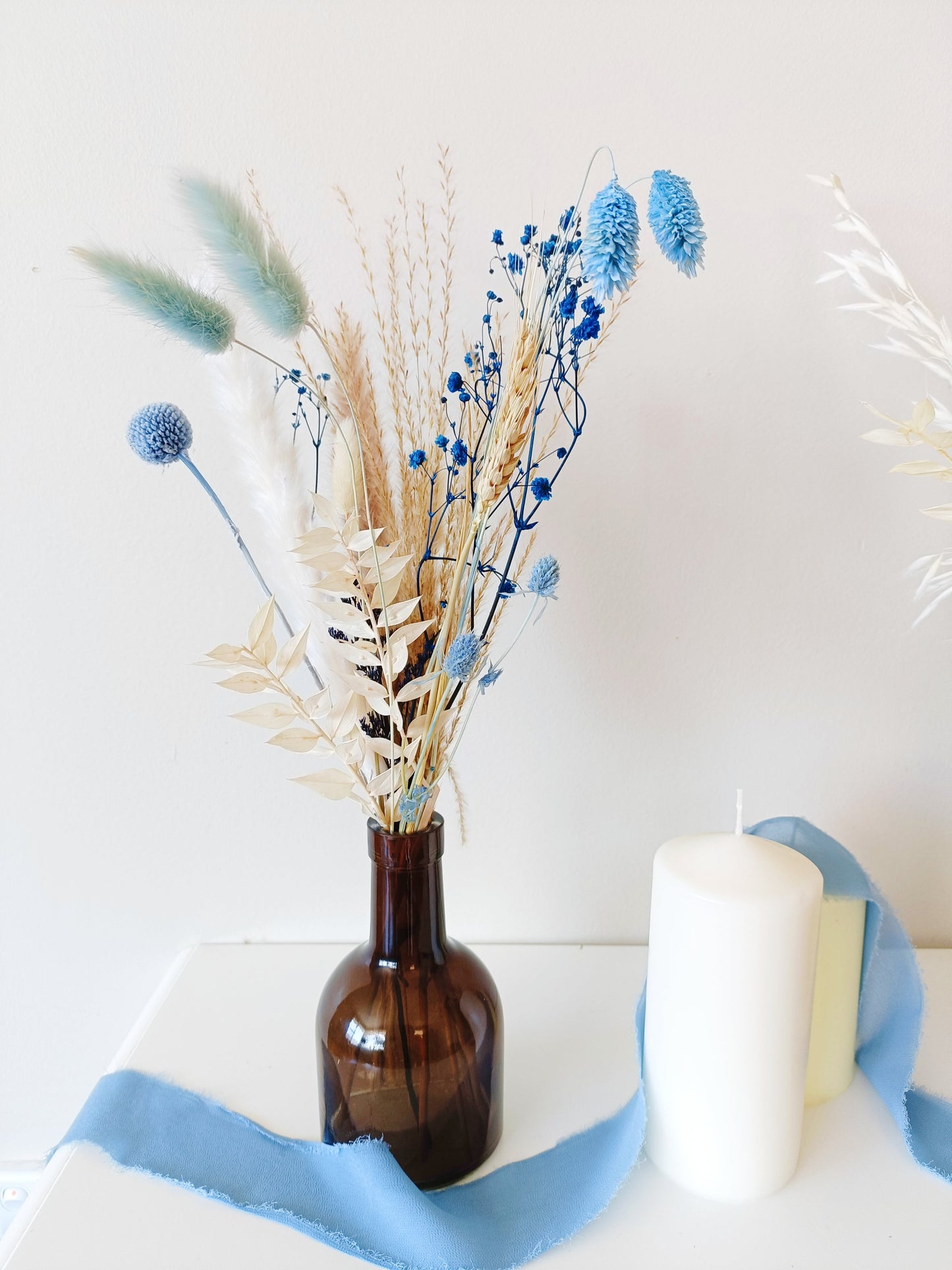 country-style flower decor, dustu blue flower setup, boho wedding flowers, vintage-inspired floral decor, delicate flower arrangement, stylish dried flower vase, timeless dried flowers, elegant table styling, wedding reception florals, beige flower display, soft aesthetic floral decor, dried palm leaf bouquet, artistic dried flowers, trendy boho arrangement, unique floral table setting, charming wedding centerpiece, aesthetic bohemian wedding, pampas grass styling, dreamy floral arrangement, light-to