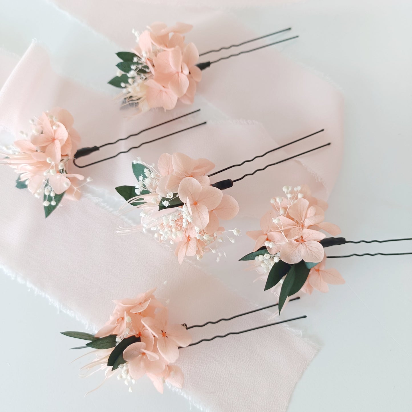 Set of blush peach dried flower hair pins for brides or bridesmaids, styled on soft pink fabric