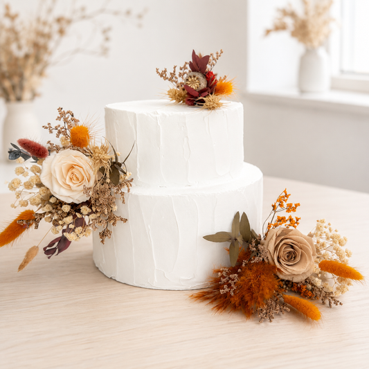 Handmade wedding cake floral decorations in amber and ivory tones, arranged with ivory roses, amber blooms and burnt orange dried foliage.