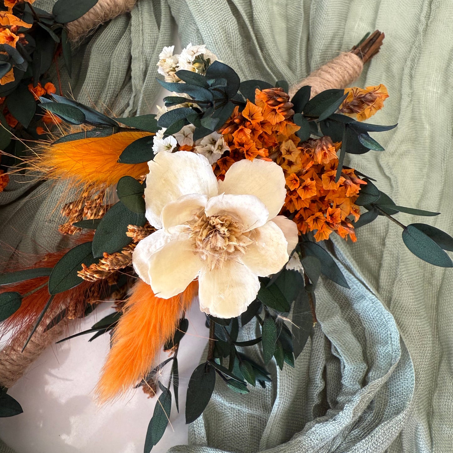 Boho wedding boutonniere with orange dried flowers, cream accent bloom and greenery
