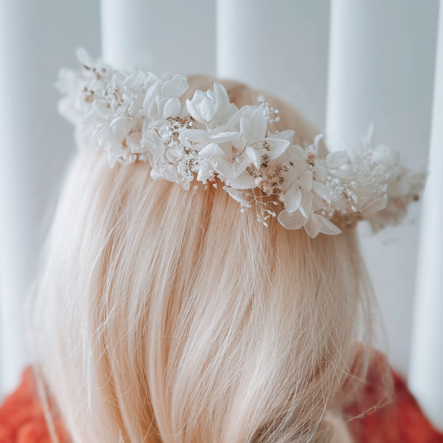 Person with blonde hair wearing a floral headband against a white background