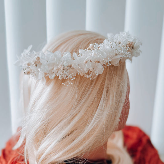 White bridal flower crown close-up on blonde hair, delicate wedding headpiece with preserved flowers