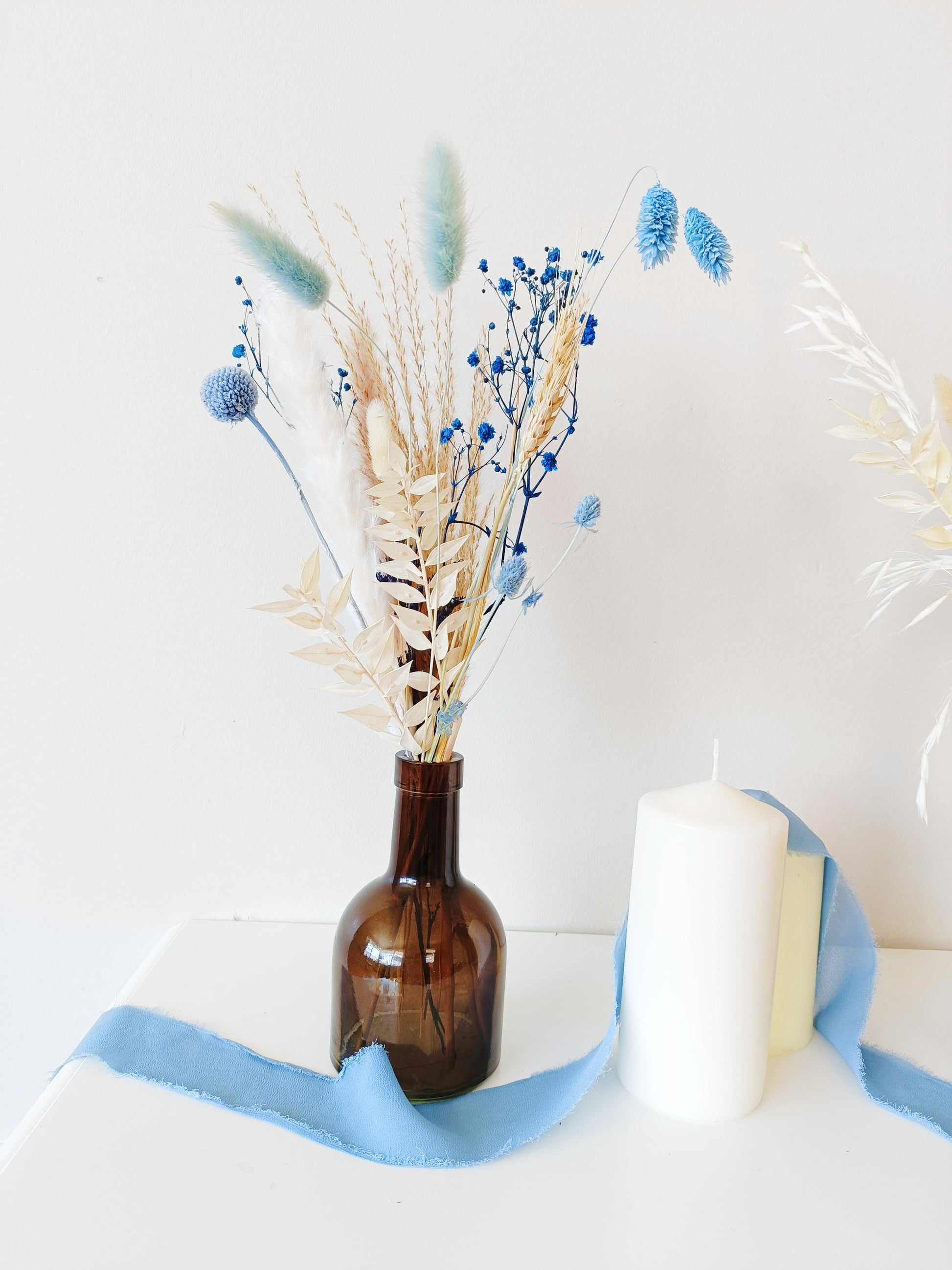 dustu blue wedding flower setup, classic boho wedding flowers, vintage-inspired floral decor, delicate flower arrangement, stylish dried flower vase, timeless dried flowers, elegant table styling, wedding reception florals, beige flower display, soft aesthetic floral decor, dried palm leaf bouquet, artistic dried flowers, trendy boho arrangement, unique floral table setting, charming wedding centerpiece, aesthetic bohemian wedding, pampas grass styling, dreamy floral arrangement