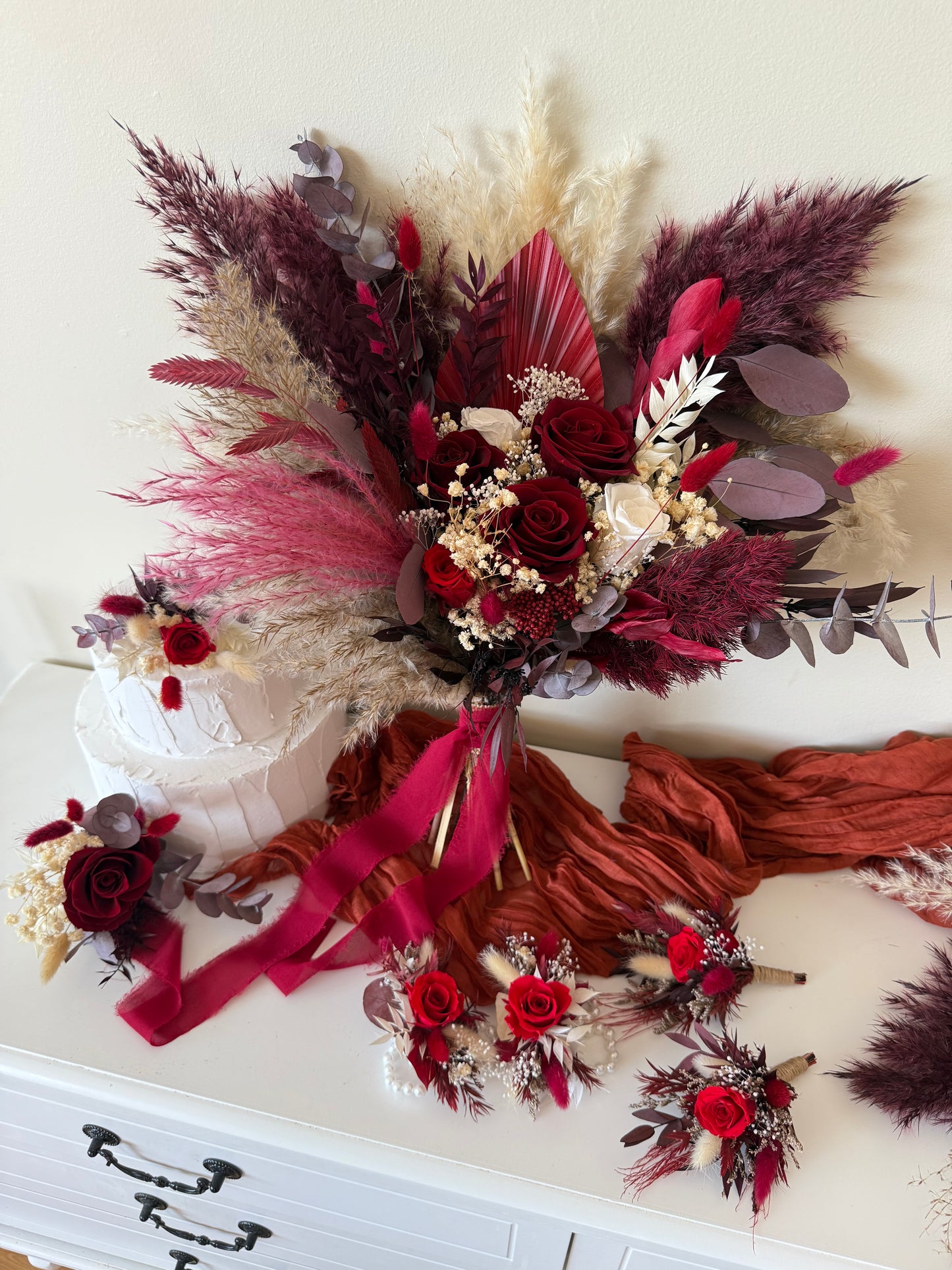 One-sided bridal bouquet in burgundy and ivory tones with pampas grass and sola wood roses, perfect for boho rustic weddings