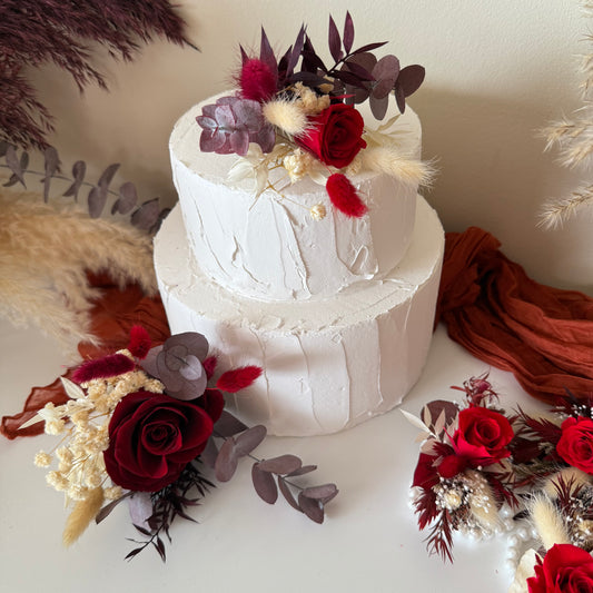 Handmade wedding cake floral decorations in burgundy and ivory tones, arranged with burgundy red roses, ivory accents and preserved eucalyptus.