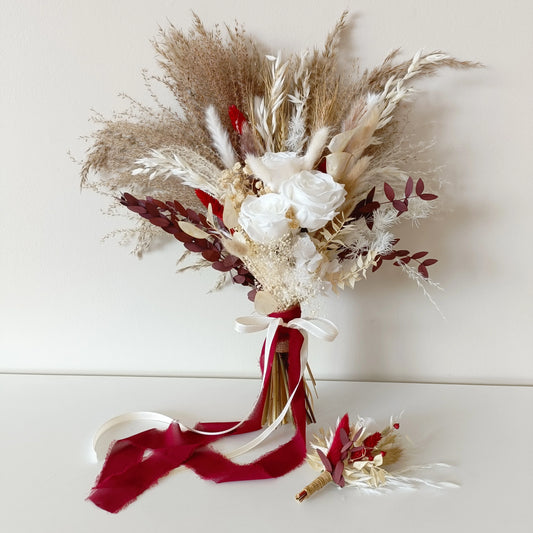 Handheld view of a dried wedding bouquet in neutral and burgundy tones, combining sola wood flowers, pampas, and dried foliage. The arrangement is wrapped with velvet ribbon for an elegant, romantic bridal look. Made to last and ship Australia-wide.