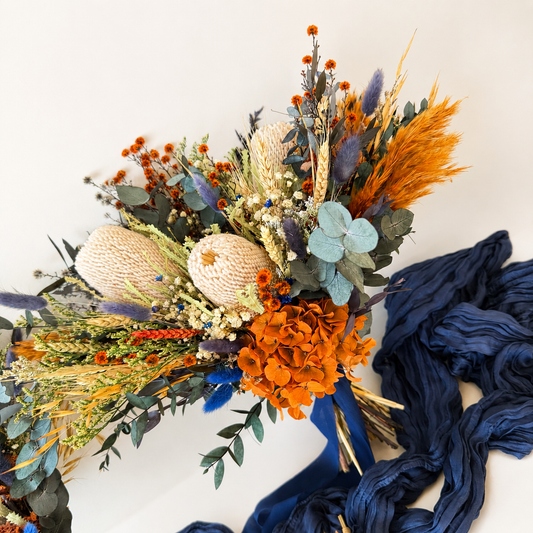 Large Australian native bridal bouquet with preserved banksia, burnt orange hydrangea, eucalyptus and dried flowers in navy blue wedding colours.