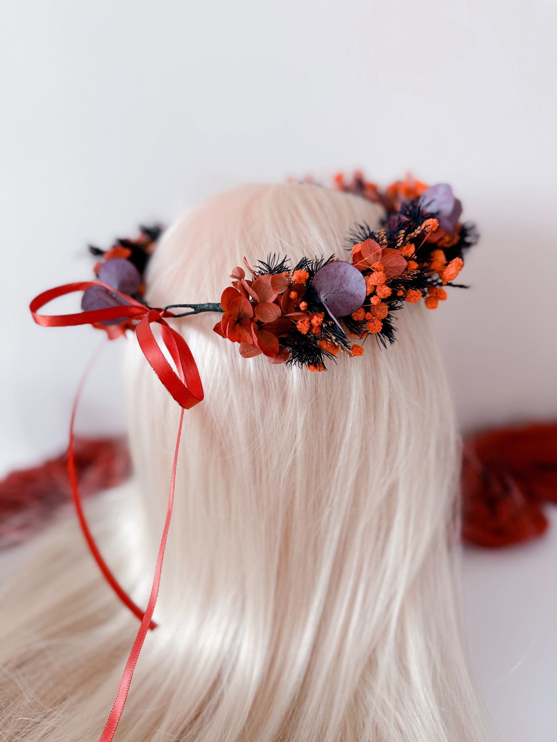 Side view of burnt orange and plum flower crown with preserved blooms and eucalyptus leaves.