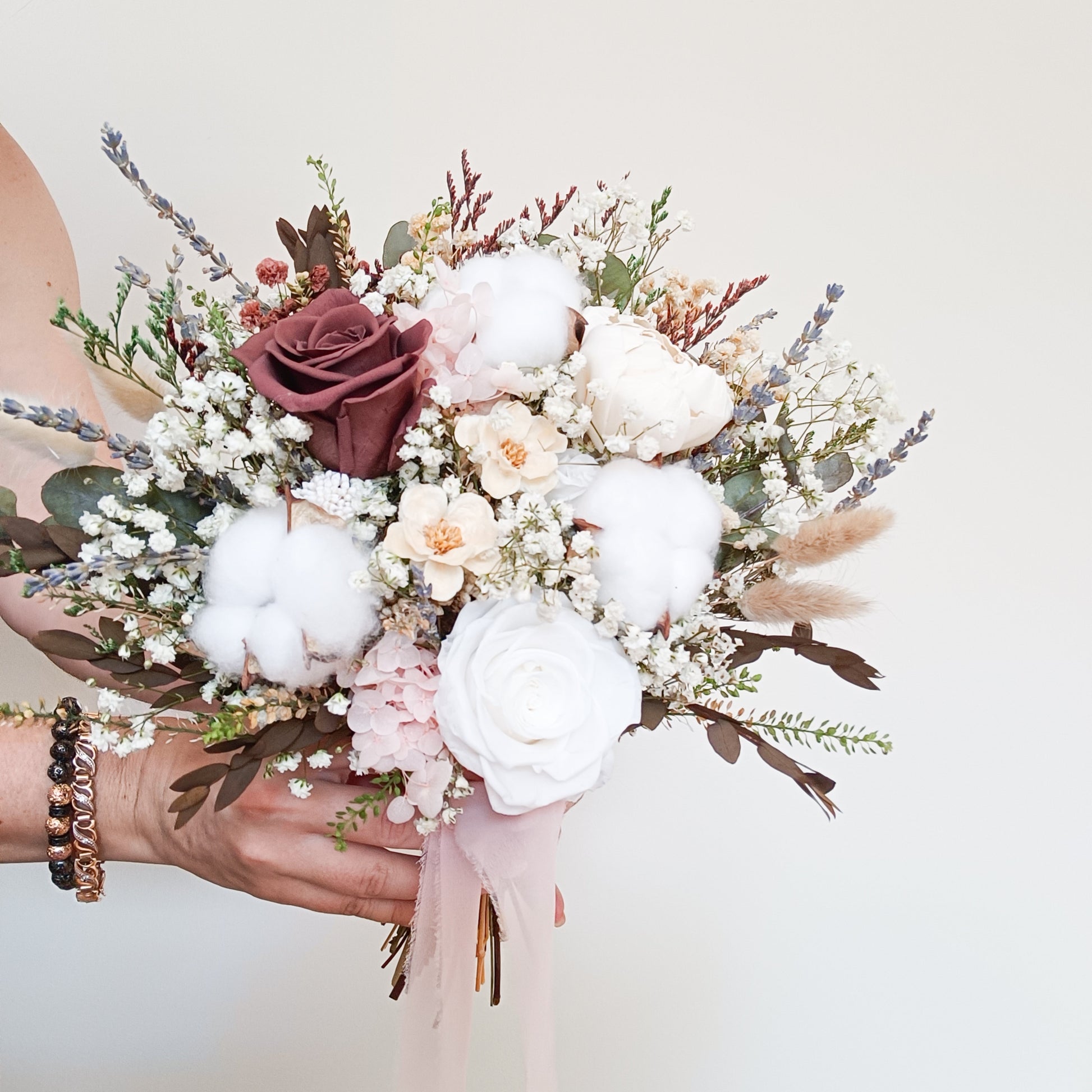 Dried cotton bouquet with white roses and wine-colored preserved flowers – boho wedding arrangement shown in natural light.