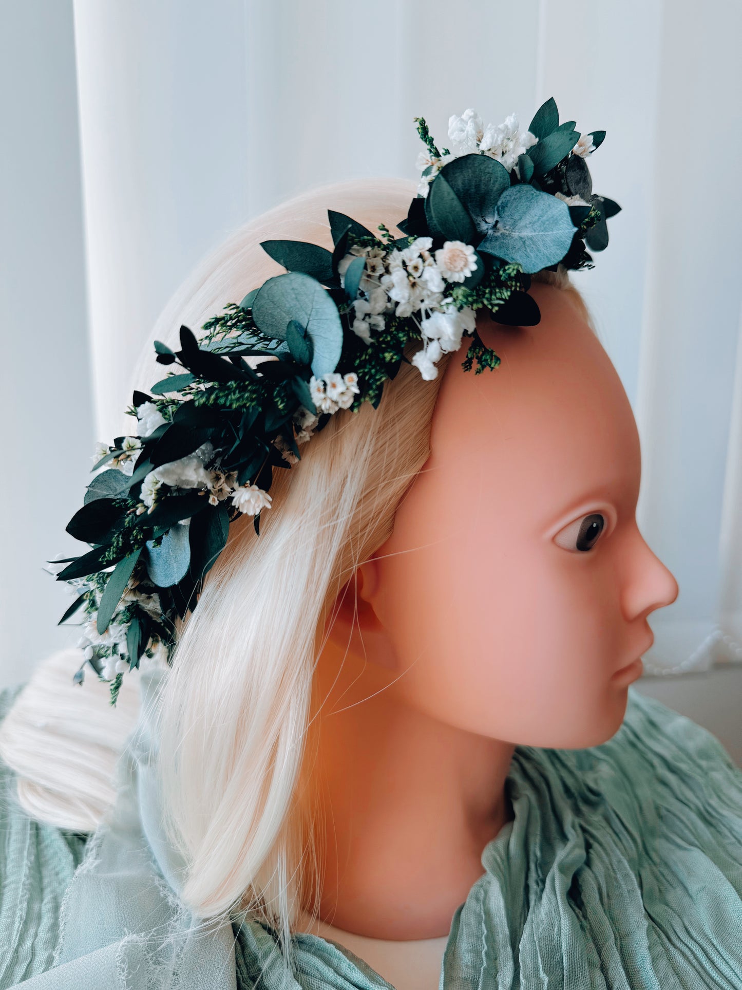 Close-up of dried flower crown showing eucalyptus leaves, small white flowers, and berry accents.