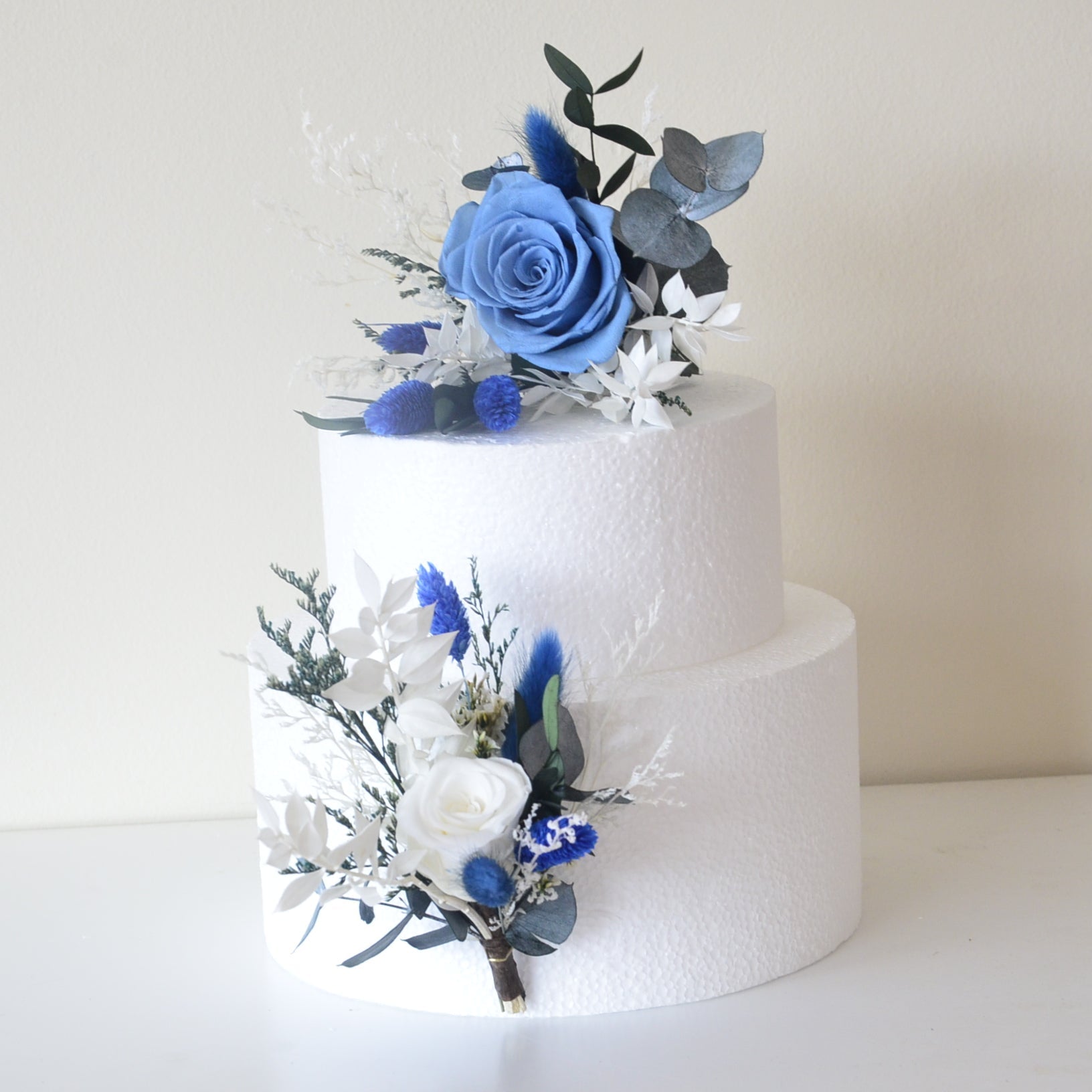 Two-piece dried flower cake topper with blue rose and preserved foliage for modern wedding cakes