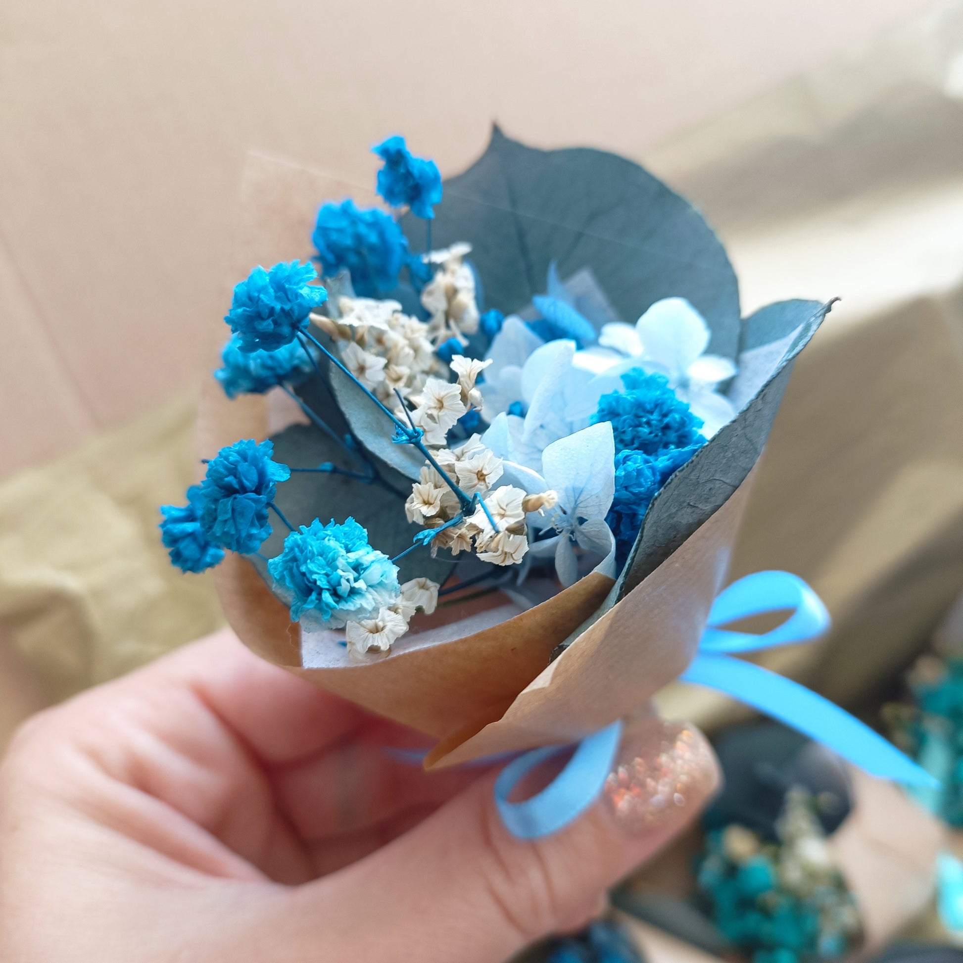 Close-up of preserved teal dried flower bouquet with natural paper wrap and eco ribbon.