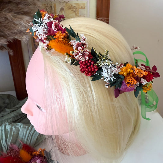 dried flower crown in vibrant autumn tones with preserved red, orange, and white flowers, worn on a blonde mannequin head.