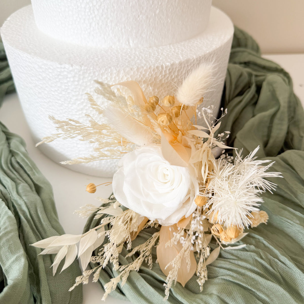 Natural dried and preserved cake topper arrangement featuring ivory white roses and delicate neutral dried flowers for a romantic boho wedding.