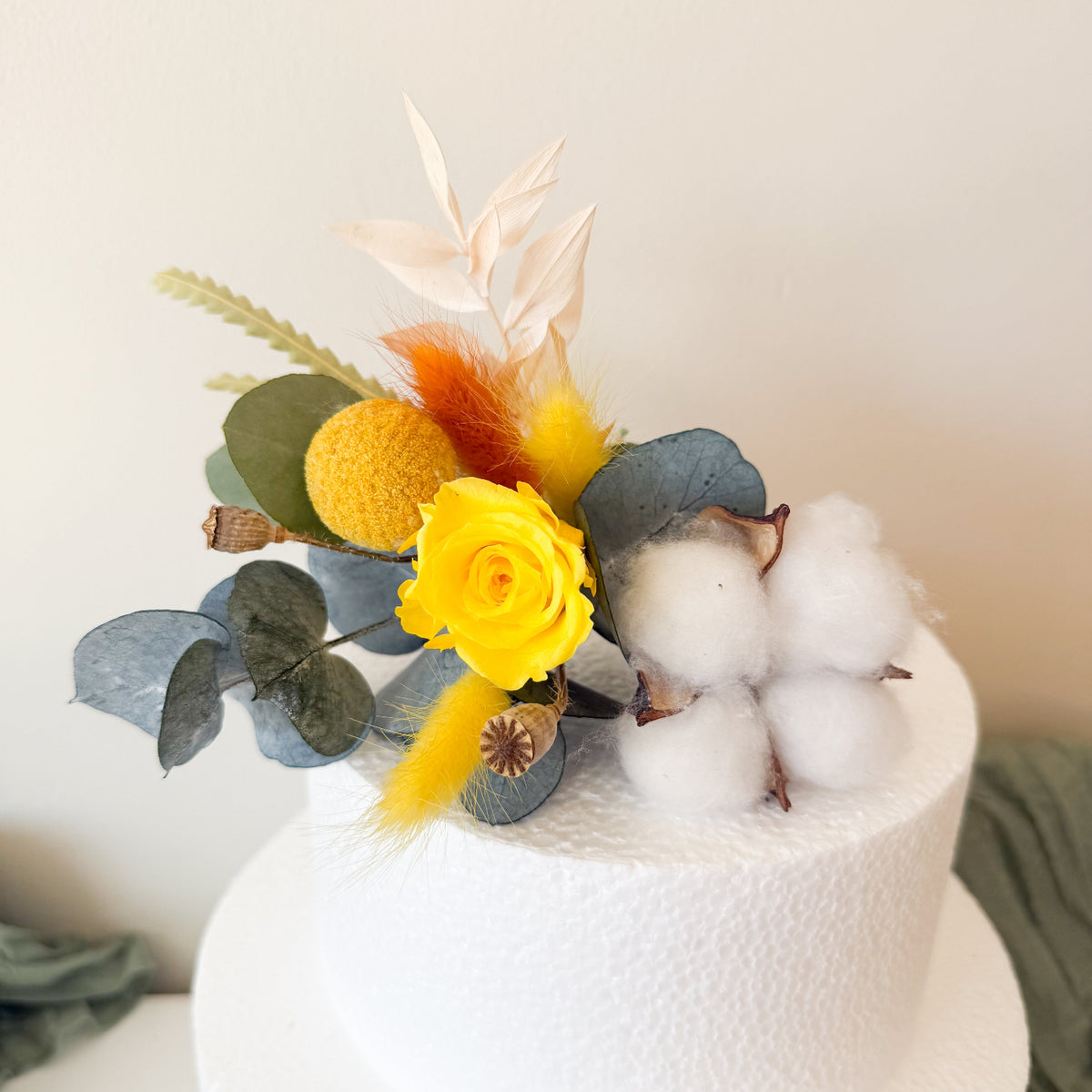 Elegant wedding cake styling with yellow sola roses, billy buttons and eucalyptus in a rustic, modern botanical palette.