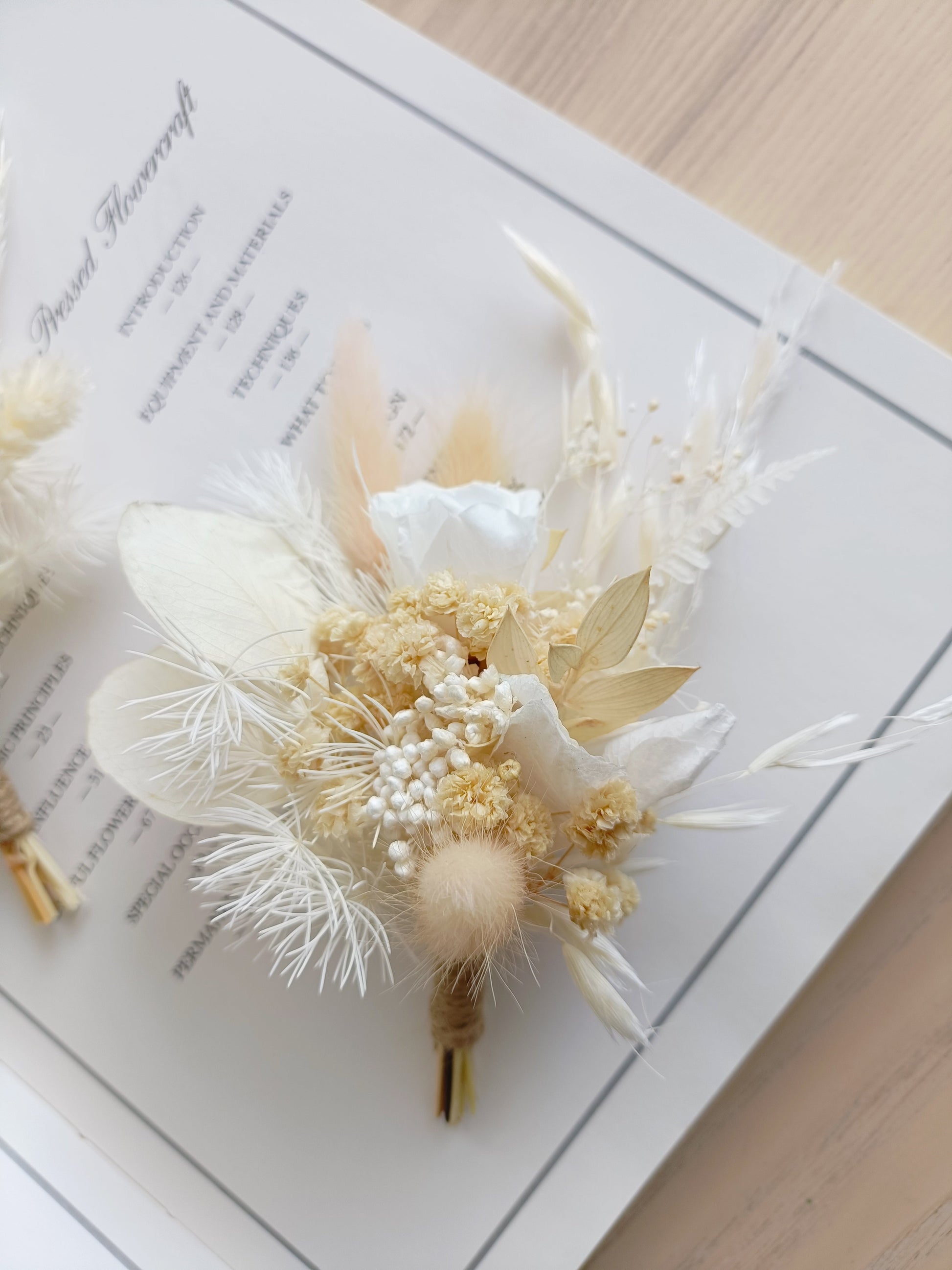 Elegant dried flower boutonniere featuring a white sola rose, preserved grasses, bunny tails, ivory blooms, and soft beige tones. Ideal for groom, groomsmen, or formal events in rustic or boho style.
