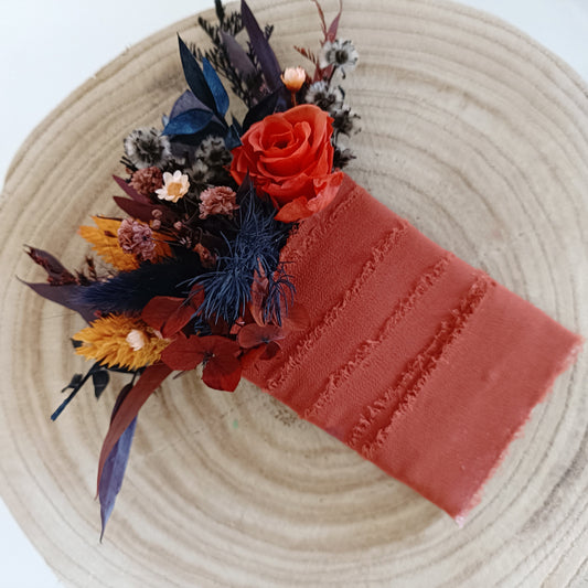 Burnt orange and blue dried boutonniere with rose, billy buttons, and textured foliage