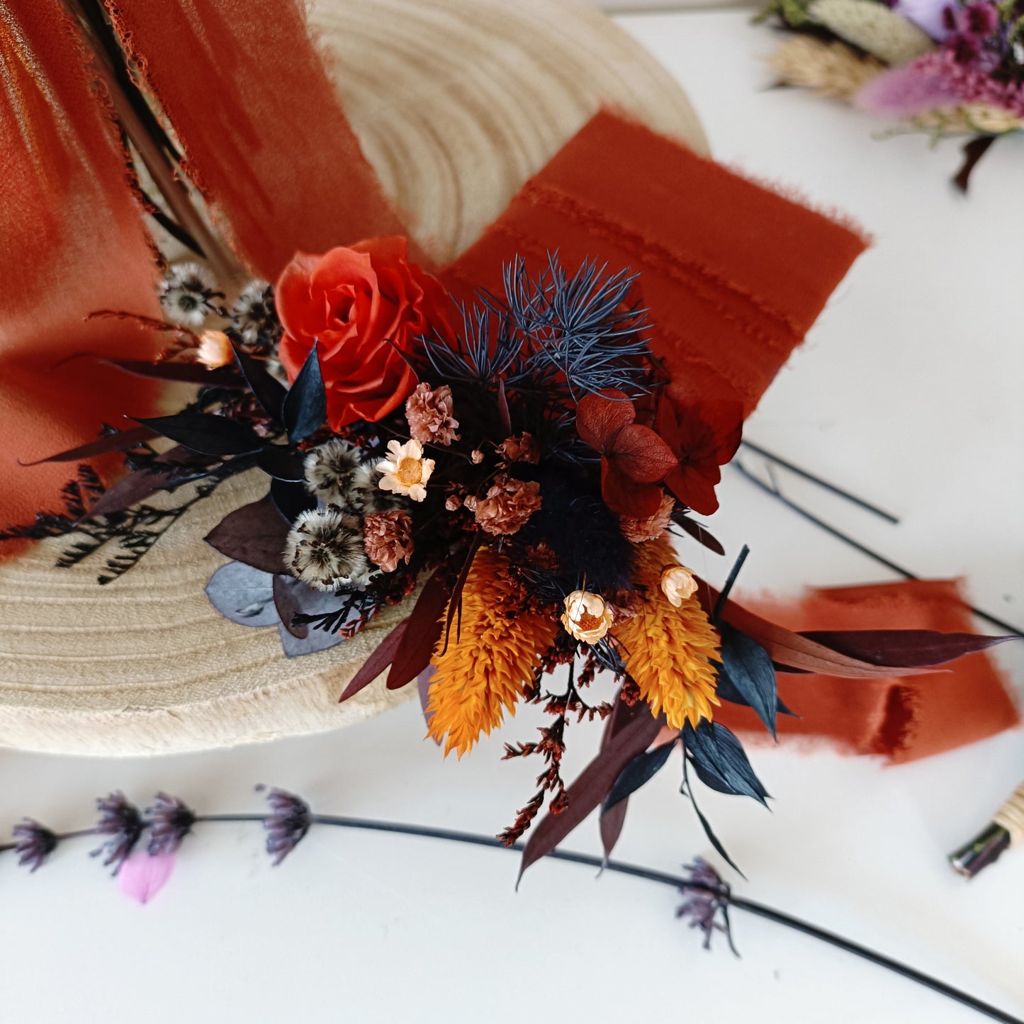 Terracotta and navy dried flower boutonniere with preserved rose and yellow accents for boho groom