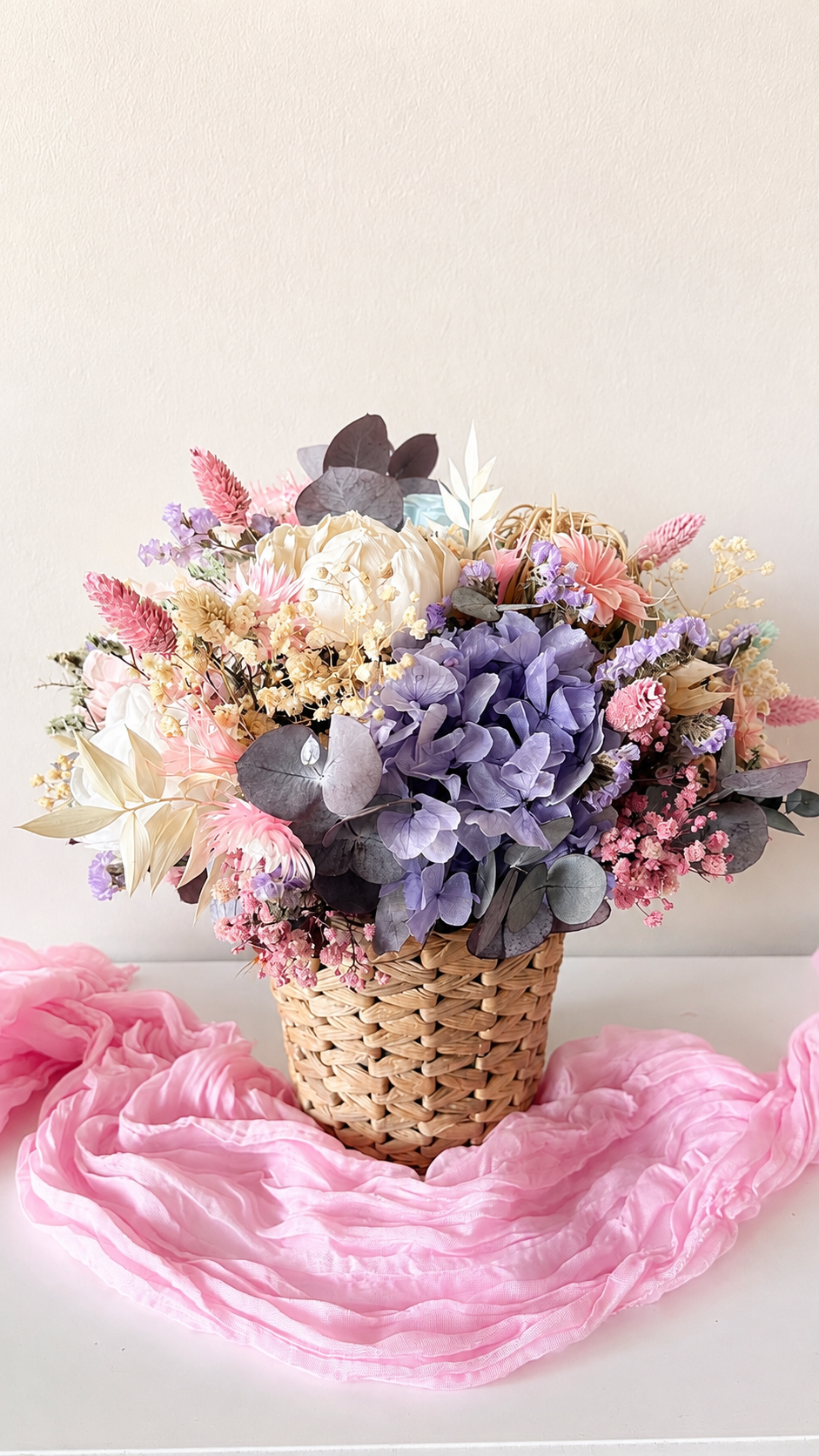 Pastel purple and pink dried flower arrangement with preserved hydrangea and eucalyptus in a woven basket