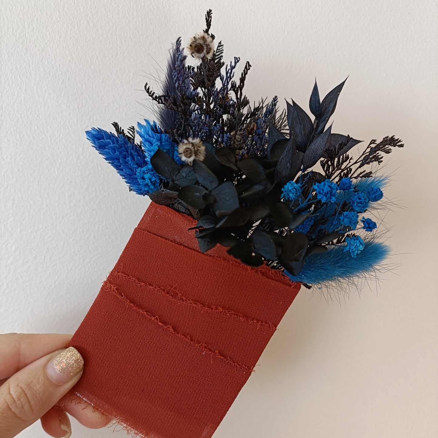 Modern dried flower boutonniere in navy blue and black with preserved hydrangea and terracotta ribbon